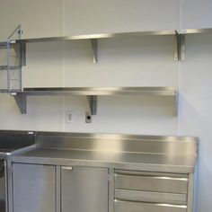 an empty kitchen with stainless steel cabinets and shelves on the wall above it is a sink