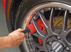 a person is cleaning the rim of a car with a sponge and cloth on it