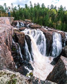 a man standing on top of a large waterfall