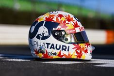 a helmet sits on the side of a race track, with leaves painted on it