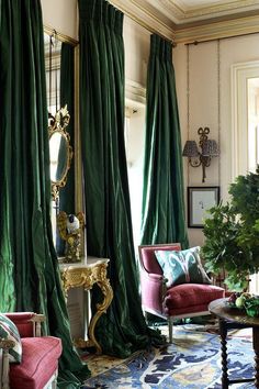 a living room filled with furniture and green drapes hanging from the ceiling next to a mirror