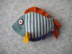 a stuffed fish is sitting on a tablecloth with blue, white and orange stripes