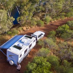 an aerial view of two recreational vehicles parked in the woods next to a body of water