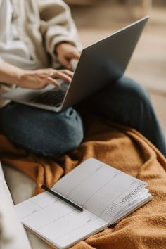 a person sitting on a couch with a laptop and notepad in front of them