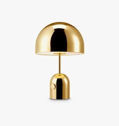 a gold table lamp with a black shade on the base and a white light behind it