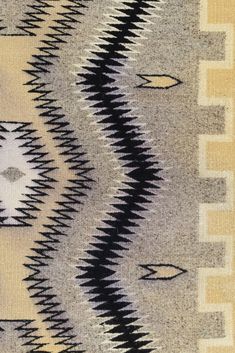 an old rug with black and white designs on it's edges, in neutral tones