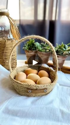 a basket filled with eggs sitting on top of a table next to potted plants