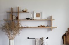 two wooden shelves on the wall with towels and vases in front of each shelf