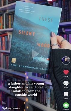 someone holding up a book in front of a bookshelf with the title, these silent wood