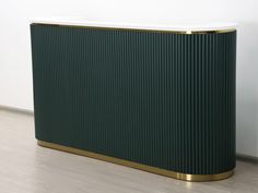 a green and gold cabinet sitting on top of a hard wood floor next to a white wall