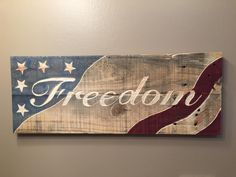 a wooden sign with the word freedom painted on it in white and red colors, hanging on a wall