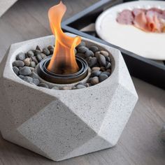 a table topped with a bowl filled with food and a fire pit on top of it