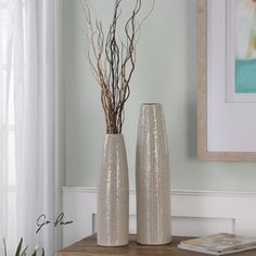 two silver vases sitting on top of a wooden table