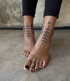 a woman's feet with tattoos on them and black nail polishes in the shape of snowflakes