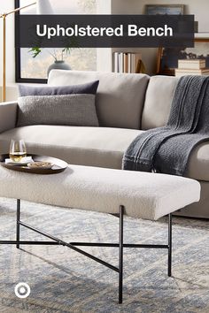 an upholstered bench in front of a couch with a tray on the end