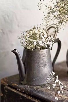 an old watering can with flowers in it