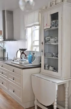 a kitchen with white cabinets and wooden floors