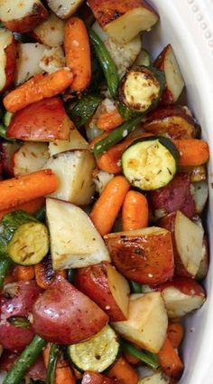 a white bowl filled with carrots, potatoes and other veggies on top of a table