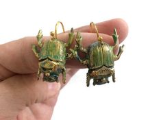 Green Beetle Earrings, Bug Earrings, Bug Jewelry These wonderful beetle earrings would make Cleopatra dance all night long. These brass beetle earrings have been hand painted with green tones so they look like they are real. The bugs are attached to gold plated ear wires to dangle from your Creepy Jewelry, Beetle Design, Beetle Earrings, Creepy Earrings, Bug Earrings, Bug Jewelry, Green Beetle, Weird Gifts, Earrings Halloween