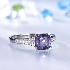 an engagement ring with a purple stone surrounded by diamonds