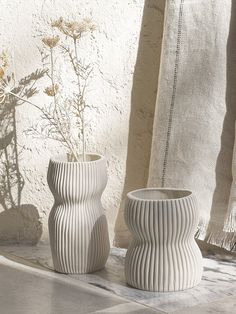 two white vases sitting next to each other on a table