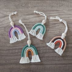 three different colored necklaces with tassels hanging from them on a wooden surface