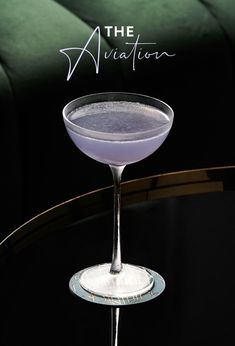 a martini sitting on top of a table next to a green couch with the words the aviation written above it