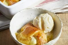 a bowl filled with food next to a white container full of ice cream on top of a wooden table