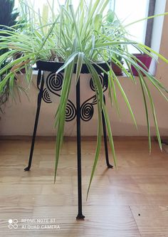 a potted plant sitting on top of a metal stand in front of a window