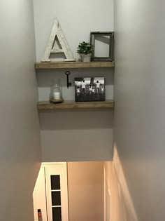 two shelves with pictures and other items on them in the corner of a room that is painted white