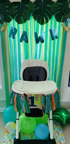 a baby's high chair with balloons and streamers in front of the table