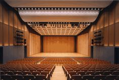 an empty auditorium with rows of seats facing the front and back, on a wooden stage