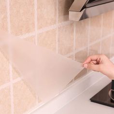 a hand is holding a roll of toilet paper in front of a faucet