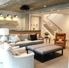 a living room filled with lots of furniture and a stair case in the back ground