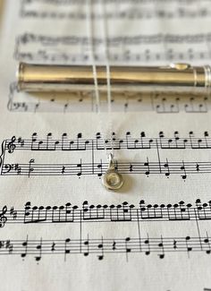 a pen sitting on top of sheet music with notes in the background and string attached to it