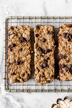 three granola bars on a cooling rack next to a bowl of oatmeal