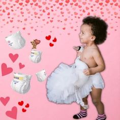 a young child in diapers and socks standing next to hearts on a pink background