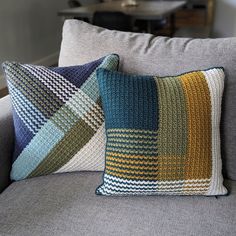 two pillows sitting on top of a gray couch