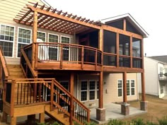 a large house with wooden stairs leading up to the upper level and second story balcony