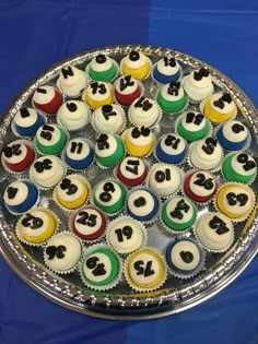 cupcakes are arranged in the shape of numbers on a cake platter that sits on a blue tablecloth