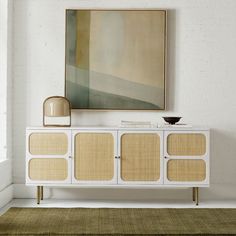 a white and beige sideboard in a living room with a painting on the wall