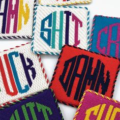 four cross stitch coasters with the word's in different colors and letters on them