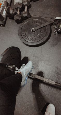 a person with their feet on the ground near a barbell and some dumbs