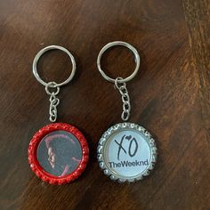 two bottle cap keychains with the words xo and the weeknd printed on them