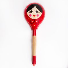 a red wooden spoon with a doll on it's side and a stick sticking out of the top