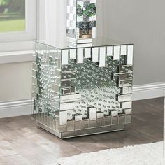 a mirrored side table sitting on top of a hard wood floor next to a window