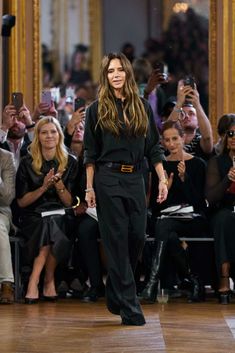 a woman walking down a runway in front of a crowd