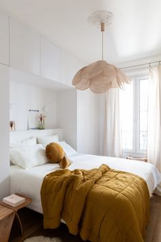 a bedroom with white walls and wooden flooring has a large bed covered in yellow blankets