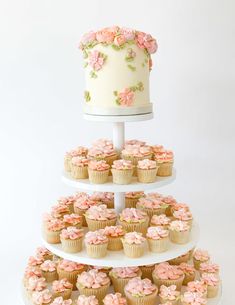 a three tiered cake with cupcakes on it