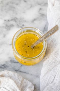 a glass jar filled with mustard sitting on top of a white towel next to a spoon